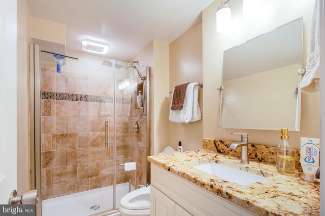 bathroom with vanity, a shower stall, and toilet