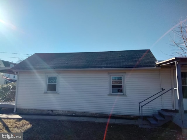 view of side of home with entry steps and a shingled roof