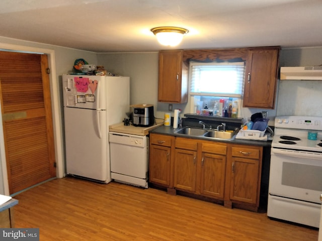 kitchen featuring under cabinet range hood, brown cabinets, white appliances, and a sink