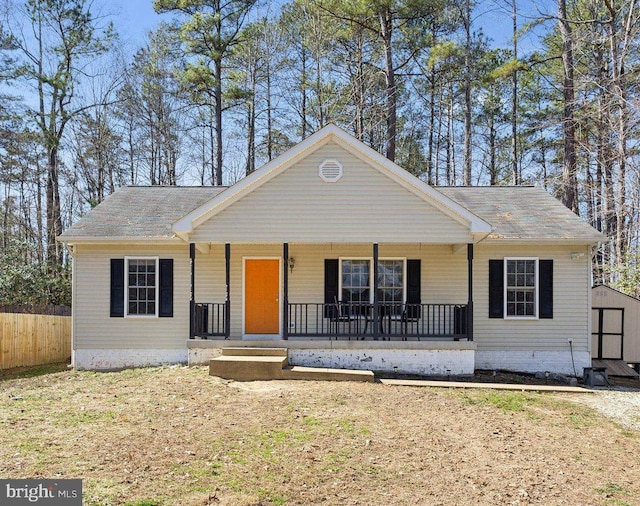 view of front of house featuring a storage shed, fence, a porch, and an outdoor structure