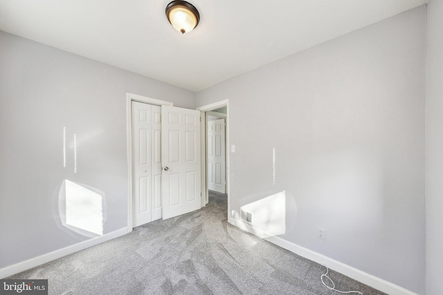 unfurnished bedroom with a closet, carpet flooring, and baseboards