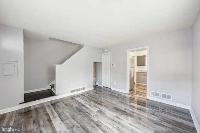 unfurnished living room featuring stairway, wood finished floors, and visible vents