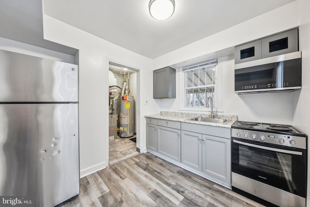 kitchen with gas water heater, appliances with stainless steel finishes, gray cabinets, and a sink