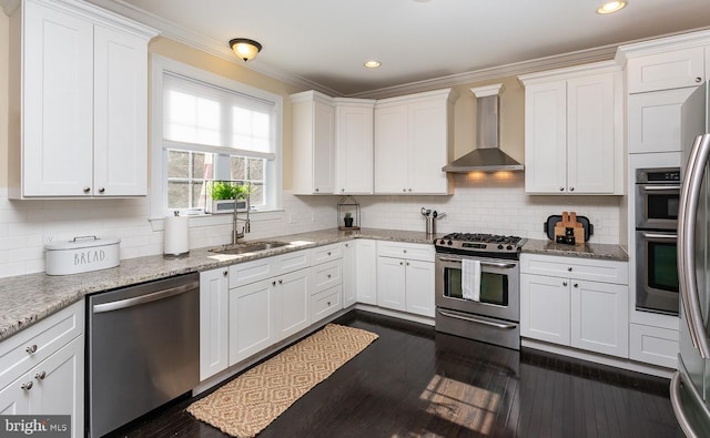 kitchen featuring decorative backsplash, stainless steel appliances, white cabinetry, wall chimney exhaust hood, and a sink