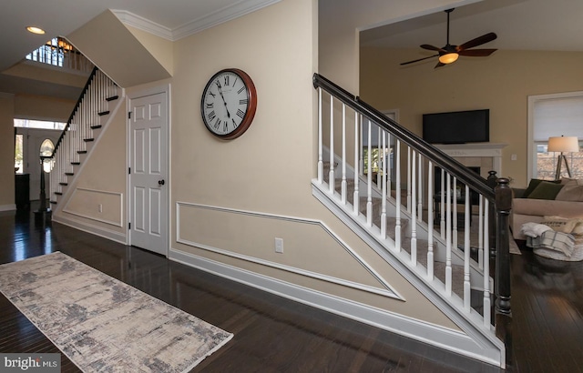 foyer featuring stairway, wood finished floors, baseboards, ceiling fan, and ornamental molding