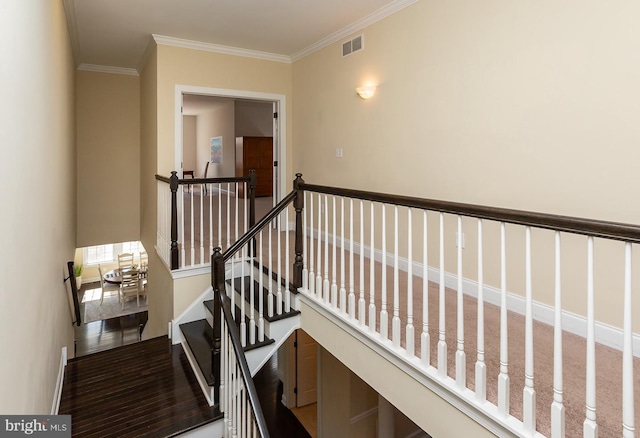 stairway with visible vents, ornamental molding, wood finished floors, baseboards, and a towering ceiling