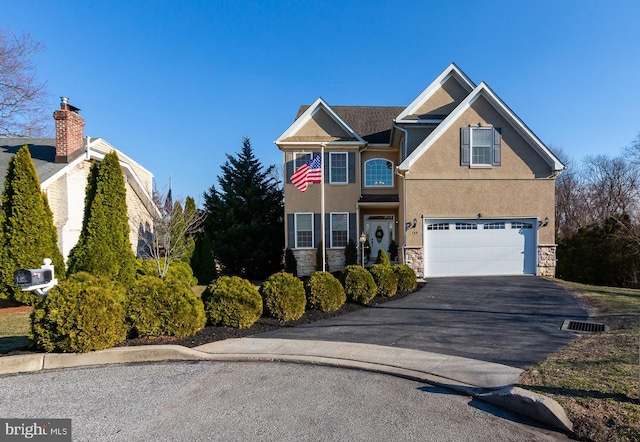 traditional-style home with a garage, stone siding, driveway, and stucco siding