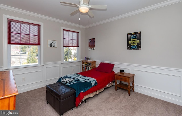 bedroom with crown molding, carpet flooring, a ceiling fan, and wainscoting