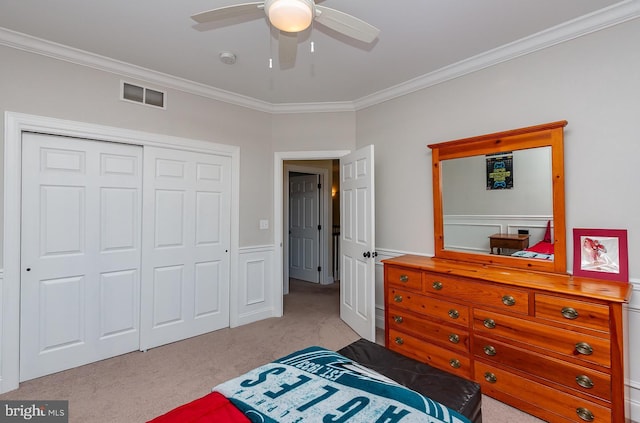 carpeted bedroom featuring a closet, visible vents, a ceiling fan, and ornamental molding