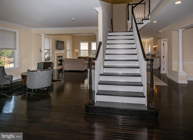 staircase with a glass covered fireplace, a wealth of natural light, and ornate columns