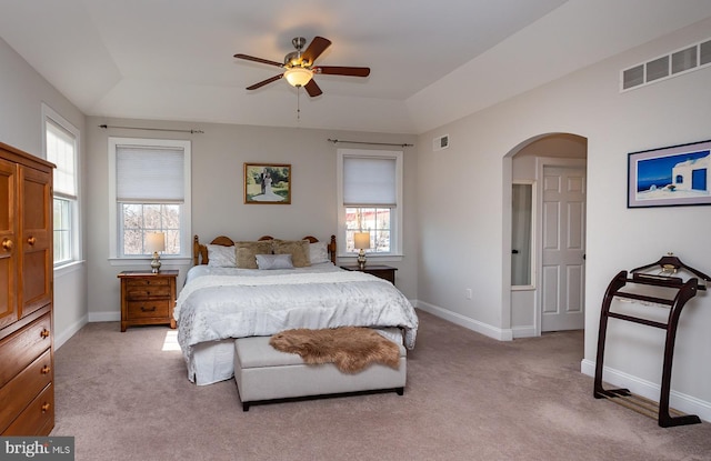 bedroom with multiple windows, arched walkways, visible vents, and light carpet