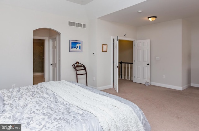 bedroom with baseboards, arched walkways, visible vents, and light carpet