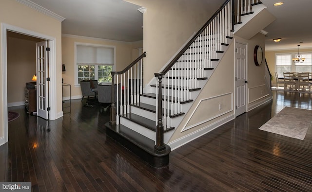 stairs with an inviting chandelier, crown molding, baseboards, and wood-type flooring