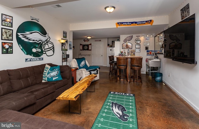 living room with a bar, baseboards, and visible vents