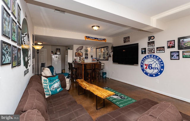 living room featuring arched walkways, visible vents, a dry bar, and baseboards