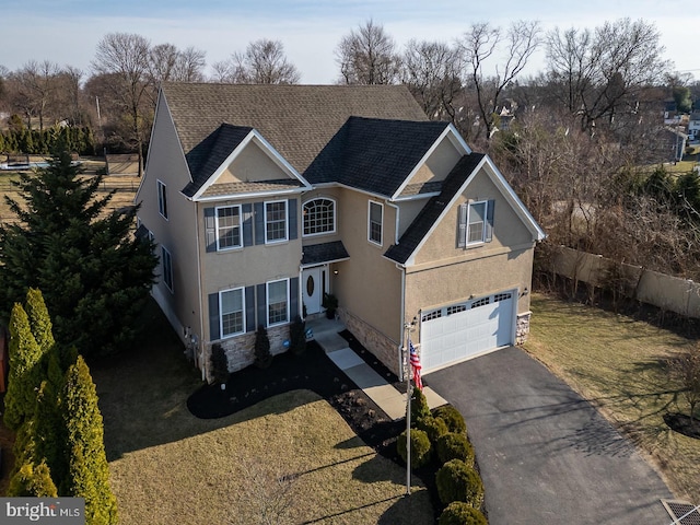 traditional-style home with aphalt driveway, an attached garage, fence, and stucco siding