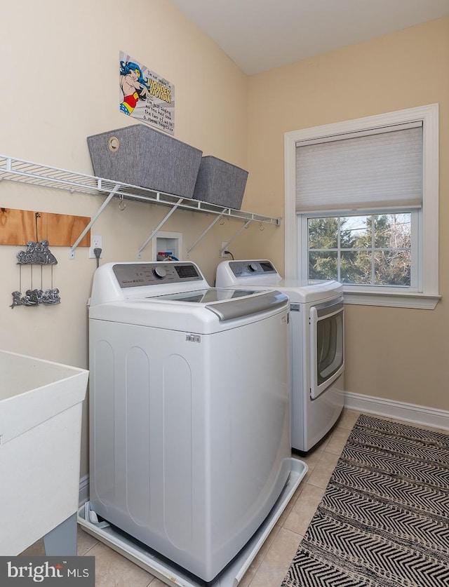 laundry room with washer and dryer, a sink, light tile patterned floors, baseboards, and laundry area