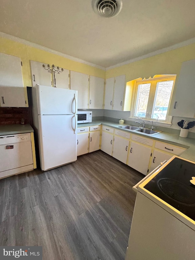 kitchen with dark wood finished floors, white appliances, visible vents, and a sink