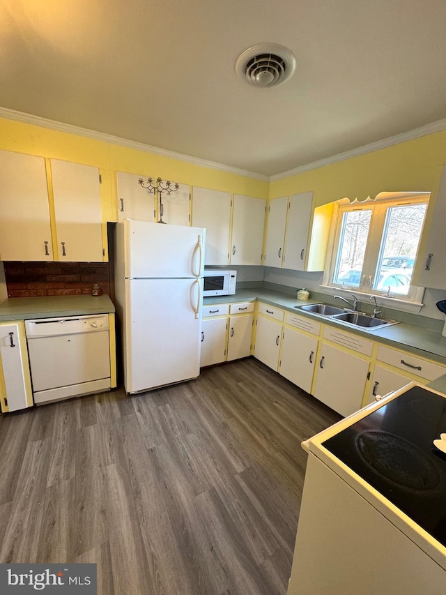 kitchen with visible vents, a sink, dark wood-style floors, white appliances, and crown molding