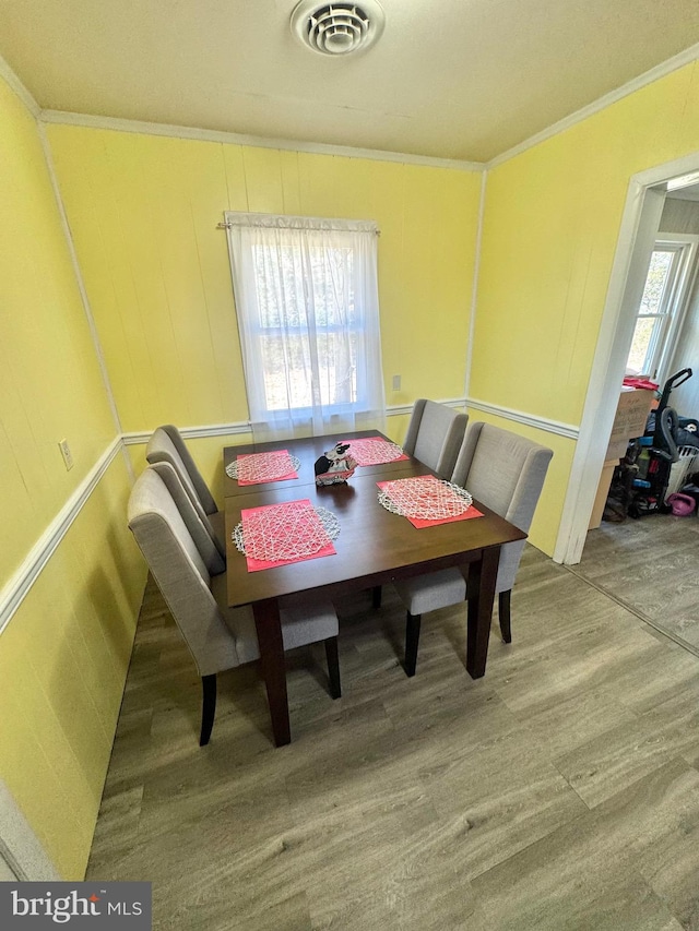 dining room with visible vents, crown molding, and wood finished floors