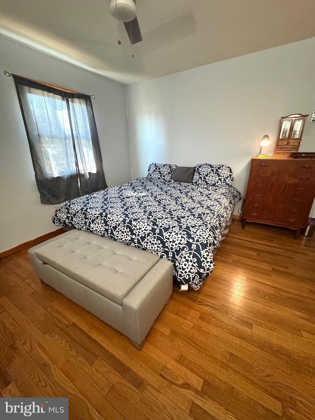 bedroom featuring ceiling fan, baseboards, and wood finished floors