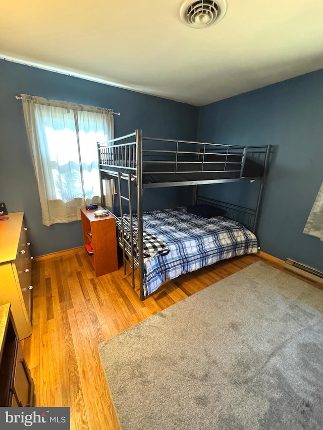 bedroom with visible vents, baseboards, and wood finished floors