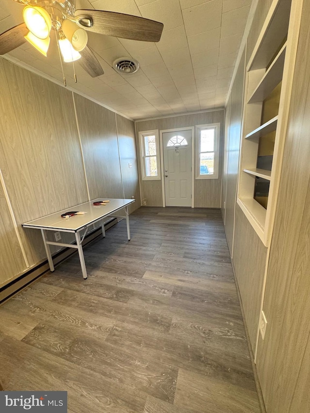 foyer with visible vents, wood walls, crown molding, and wood finished floors