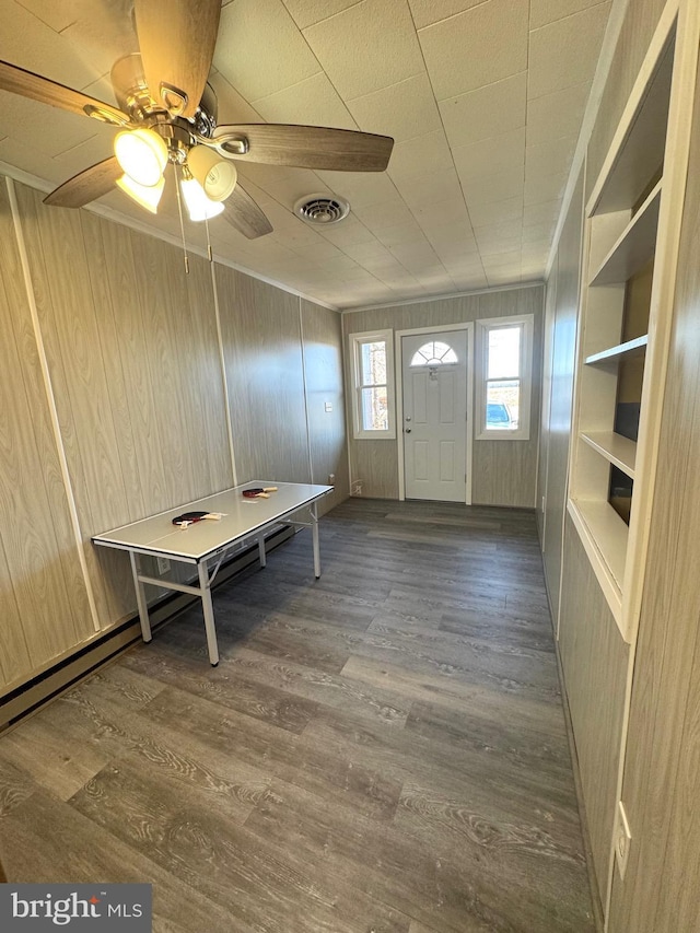 foyer featuring ceiling fan, visible vents, wooden walls, and wood finished floors