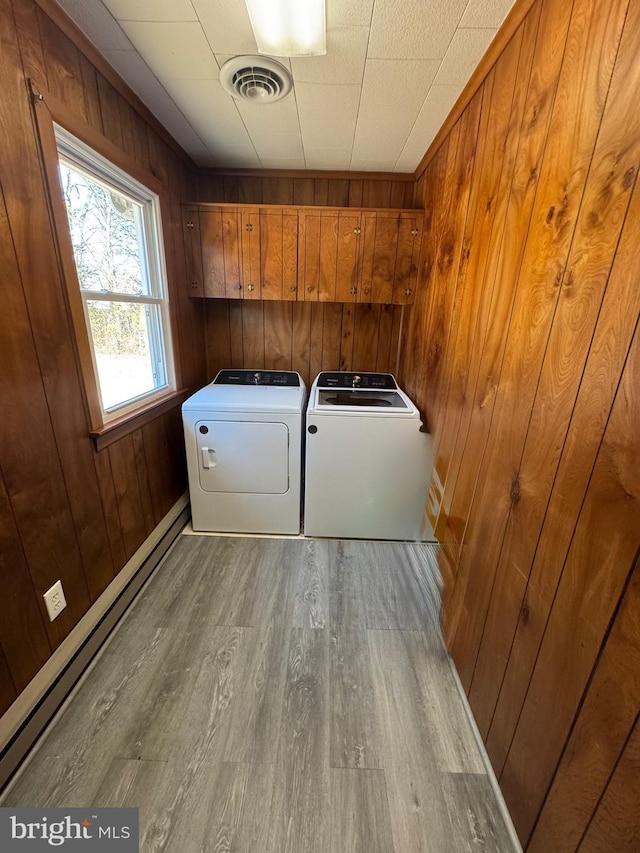 laundry room featuring visible vents, wood finished floors, cabinet space, wood walls, and baseboard heating