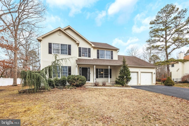 traditional home featuring aphalt driveway, roof with shingles, an attached garage, and fence