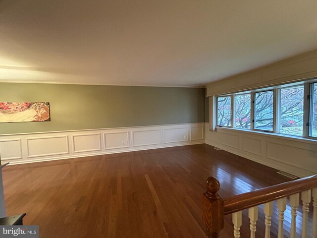 empty room featuring visible vents, dark wood finished floors, and wainscoting