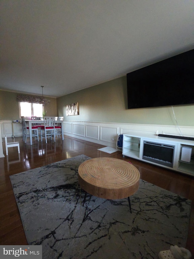 unfurnished living room featuring wainscoting, wood finished floors, and a decorative wall