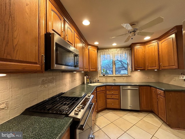 kitchen featuring light tile patterned floors, stainless steel appliances, dark countertops, and a sink