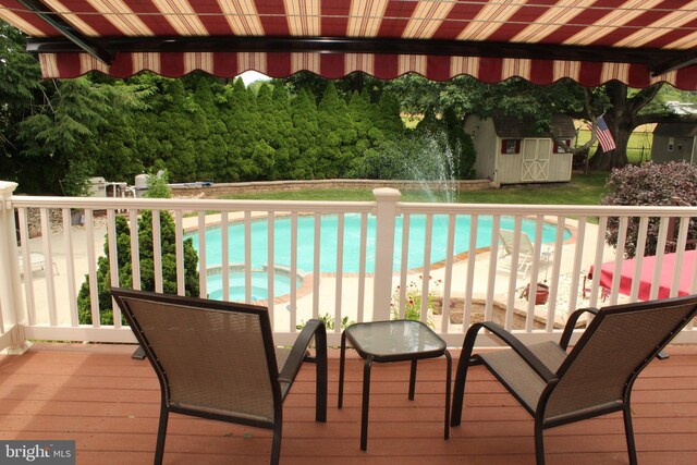 exterior space featuring a shed, a pool with connected hot tub, and an outbuilding