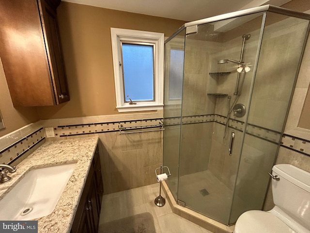 full bathroom with toilet, a stall shower, tile walls, and vanity