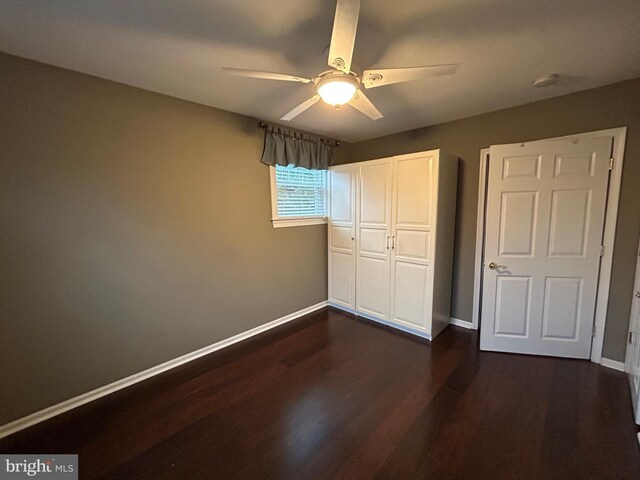 unfurnished bedroom with a closet, dark wood-style flooring, ceiling fan, and baseboards