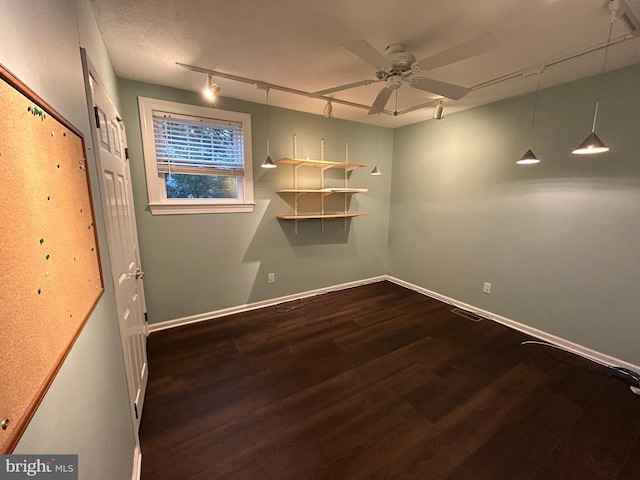 spare room featuring dark wood-style flooring, visible vents, a ceiling fan, track lighting, and baseboards