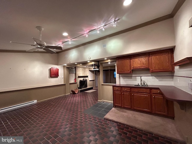 kitchen featuring a ceiling fan, dark countertops, baseboard heating, crown molding, and a sink