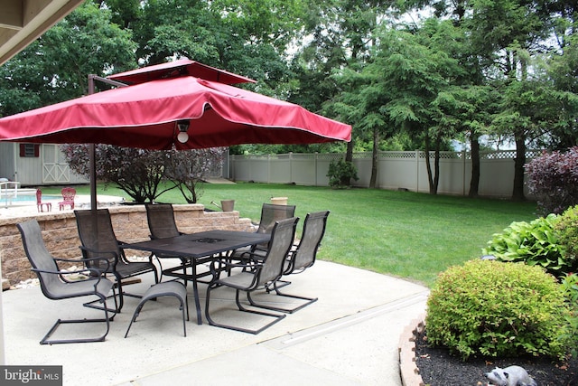 view of patio / terrace with an outbuilding, a shed, outdoor dining area, and a fenced backyard