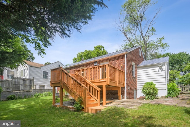 back of house featuring a lawn, fence, a wooden deck, brick siding, and stairs