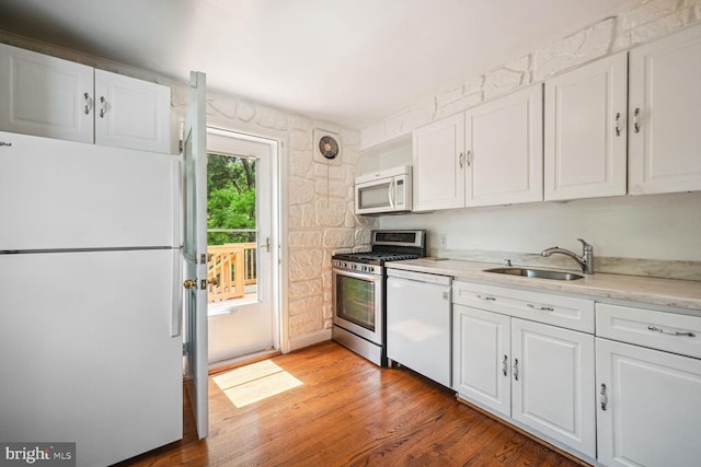 kitchen with white cabinetry, white appliances, and a sink