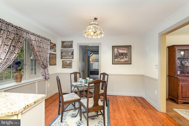 dining space featuring light wood finished floors and wainscoting