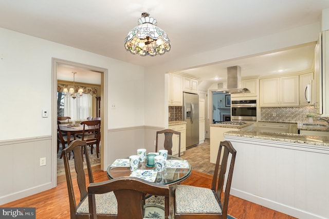 dining room featuring a wainscoted wall, a chandelier, and light wood-type flooring