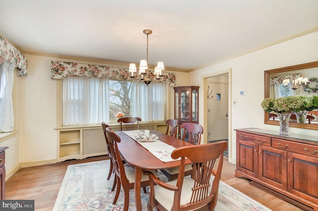 dining room featuring a notable chandelier, light wood-style flooring, and ornamental molding