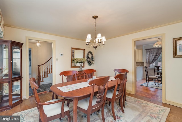 dining room with light wood-type flooring, a chandelier, stairs, and crown molding