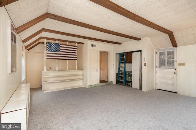 unfurnished living room featuring visible vents, vaulted ceiling with beams, and carpet