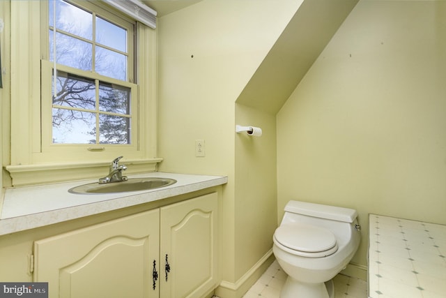 half bath featuring toilet, vanity, and baseboards