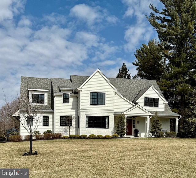 view of front of property with roof with shingles and a front lawn