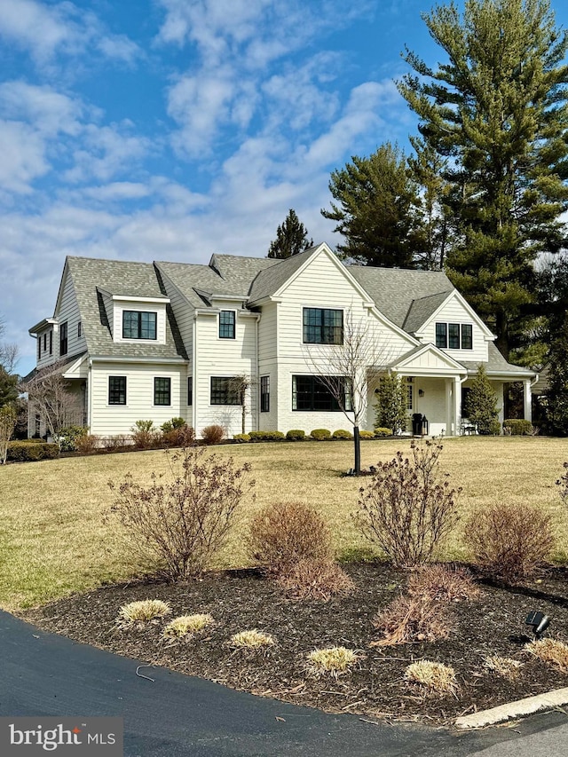 shingle-style home featuring a front lawn and roof with shingles