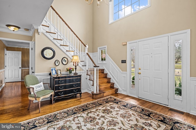 entryway featuring stairway, wainscoting, visible vents, and wood finished floors